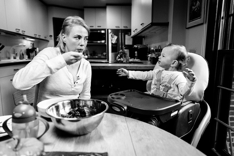 Black and white, Mother blows to cool down food before feeding it to daughter