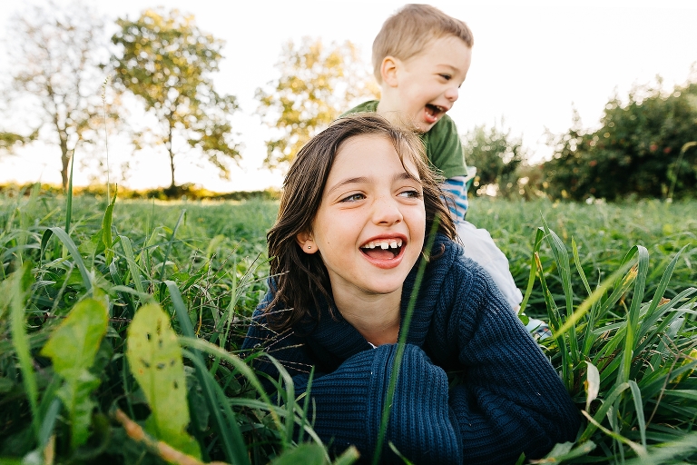 Brother and sister both laying in grass