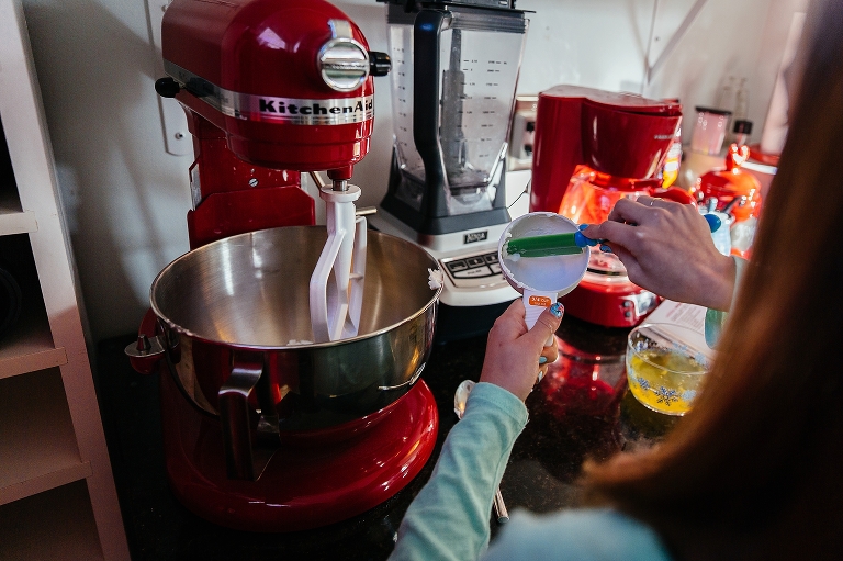Girl in kitchen baking cupcakes puts ingredients into mixer