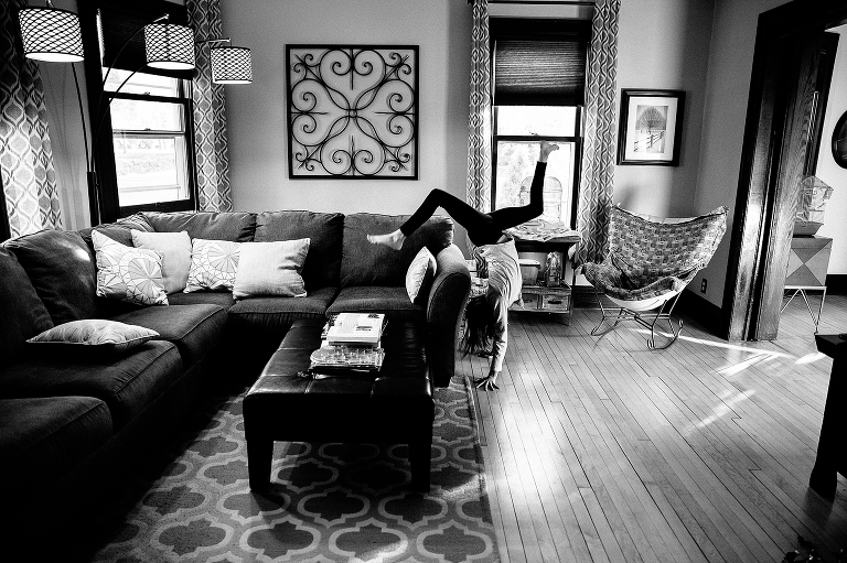 Black and white. Young girl in living room does handstand
