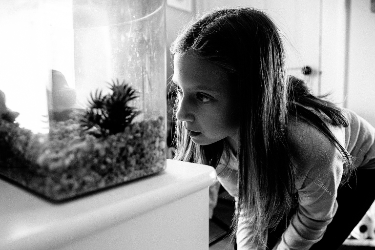 Black and white. Girl in bedroom looks into fish tank