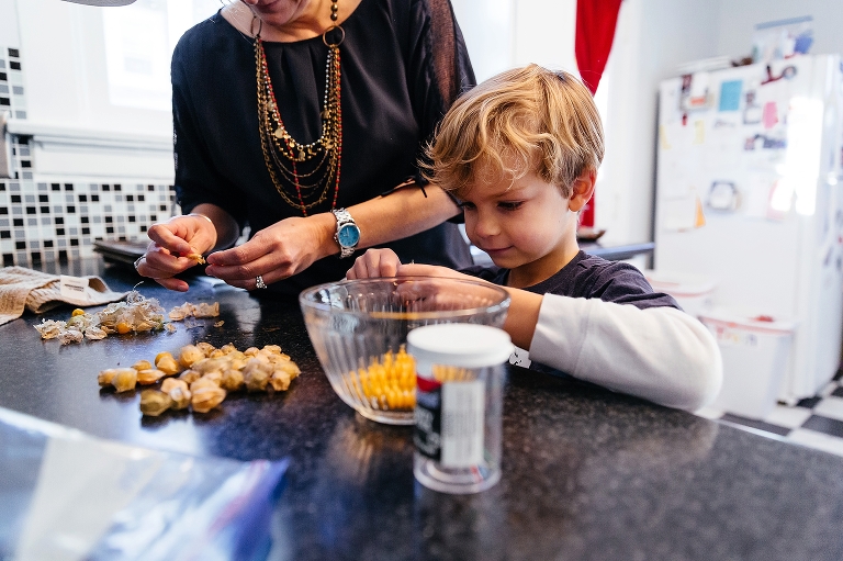 Mother and son in kitchen shell ground cherries.