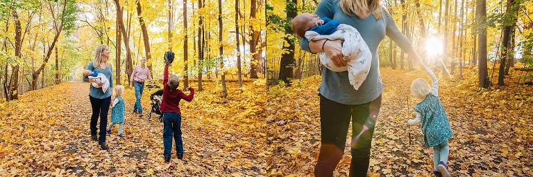 Family of five walks down trail with colored fall leaves all around them. daughter twirls, mother holds newborn, father and son play catch with baseball.