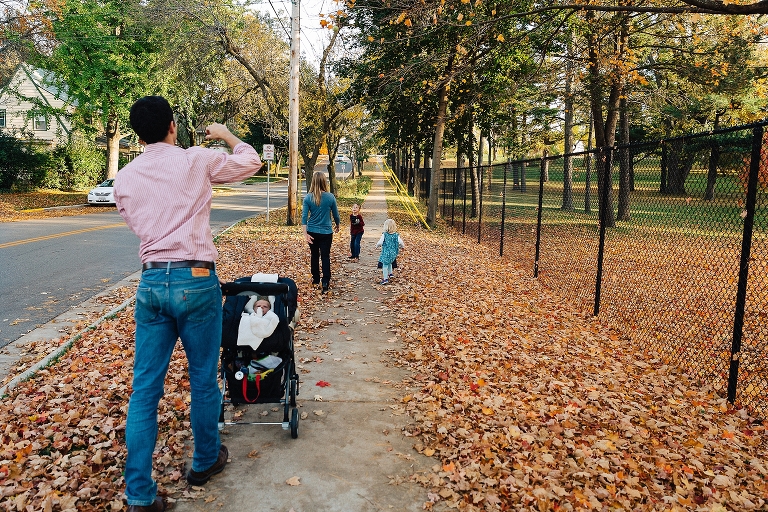 Family of five goes on a walk together at fall time with colored leaves