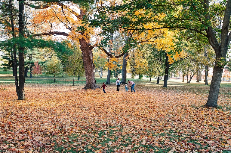 Family of five plays outside together at park at fall season with colored leaves