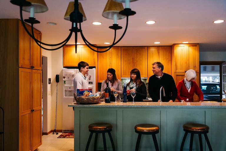 Family stands around cooking in kitchen
