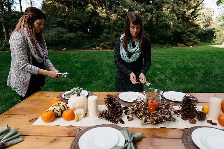 Two girls stand outside setting the table for dinner