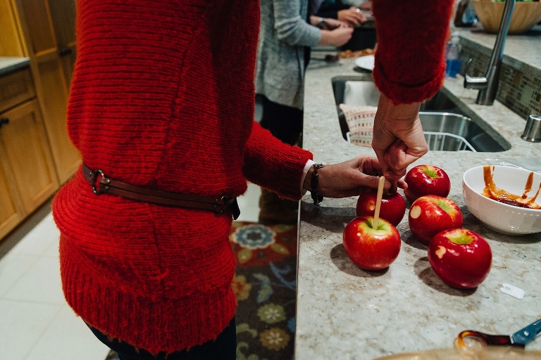 Woman puts sticks into apples before dipping them in caramel.