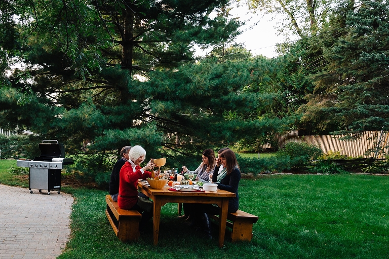 Family sits outside together at table eating dinner