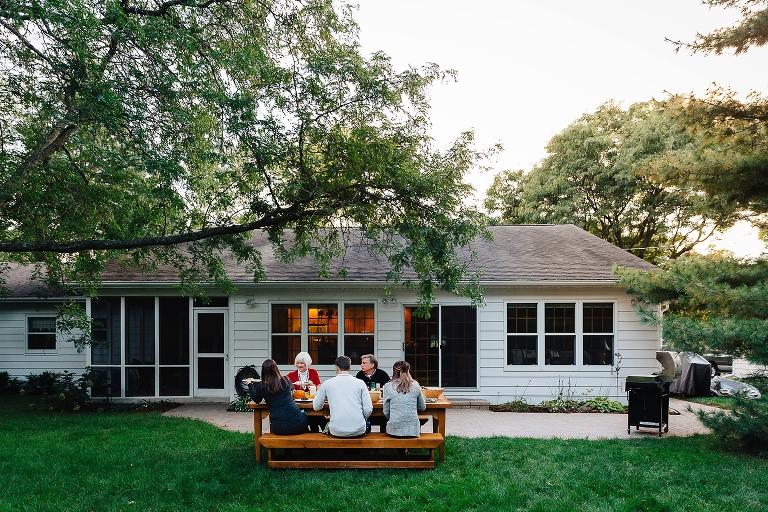 Family sits outside together at table eating dinner