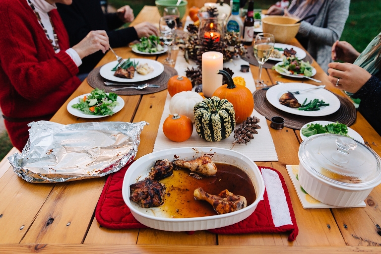 Family sits outside together at table eating dinner