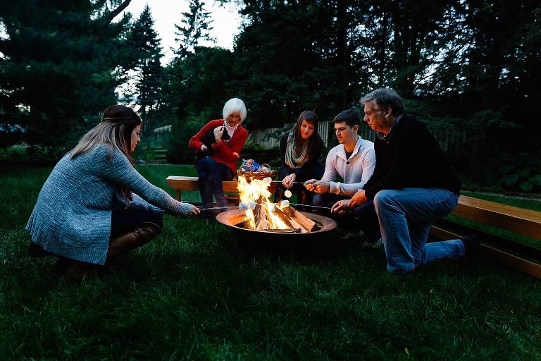 Family sits around fire pit making smores