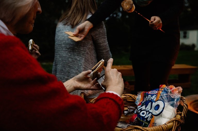 Family sits together eating smores