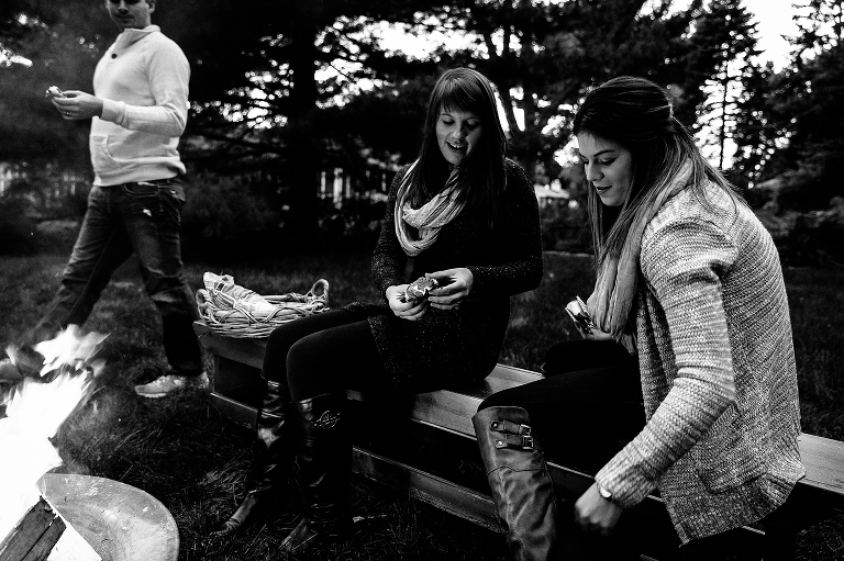 Black and white. Family sits together outside eating smores