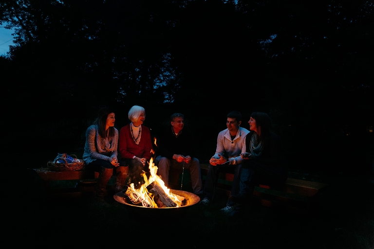 Darkness with bright fire pit and family sitting around the fire