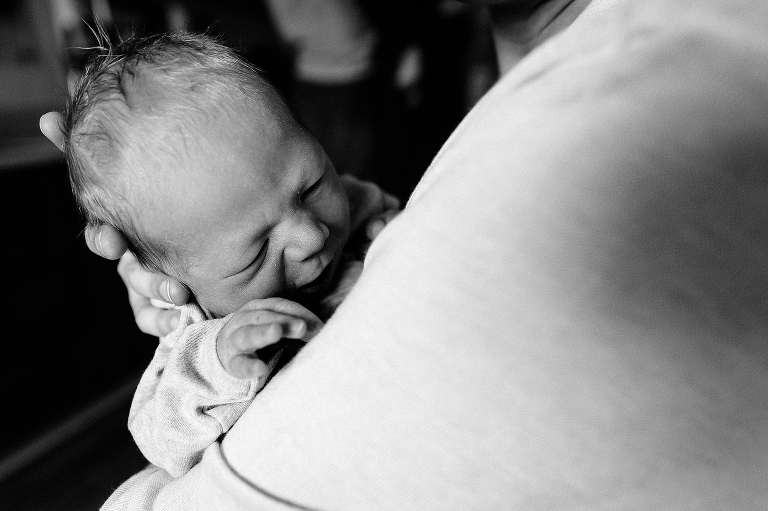 Black and white, sleeping baby's head held by parent in hospital