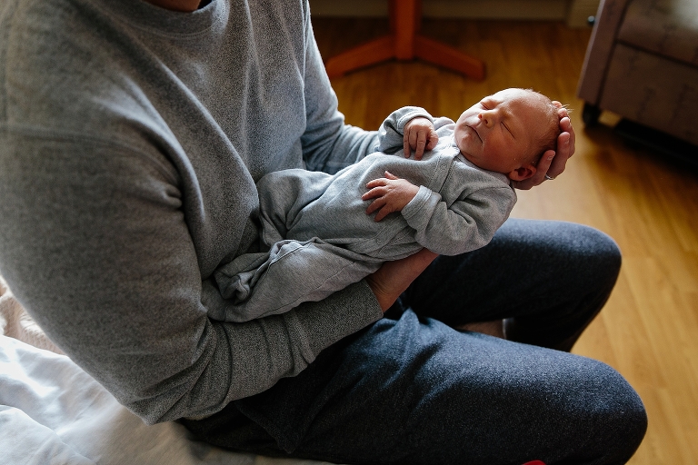 Father holds newborn son on hospital bed
