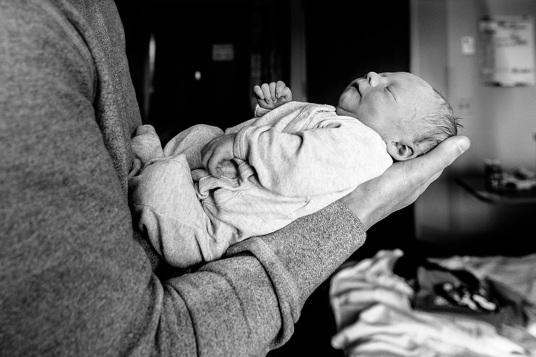 Black and white, Newborn baby in hospital sleeps in fathers arms.