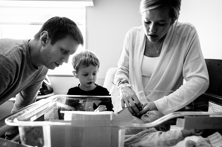 Black and white, Family watch mom change baby's outfit in hospital.