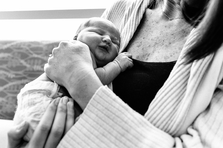 Black and white. Mother holds sleeping newborn baby boy in hospital.