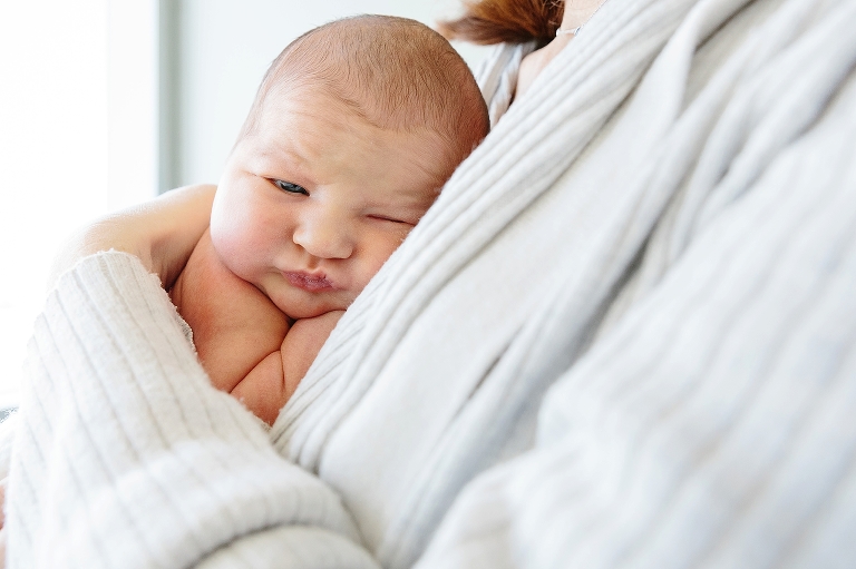 Sleepy newborn baby lays on mother chest.