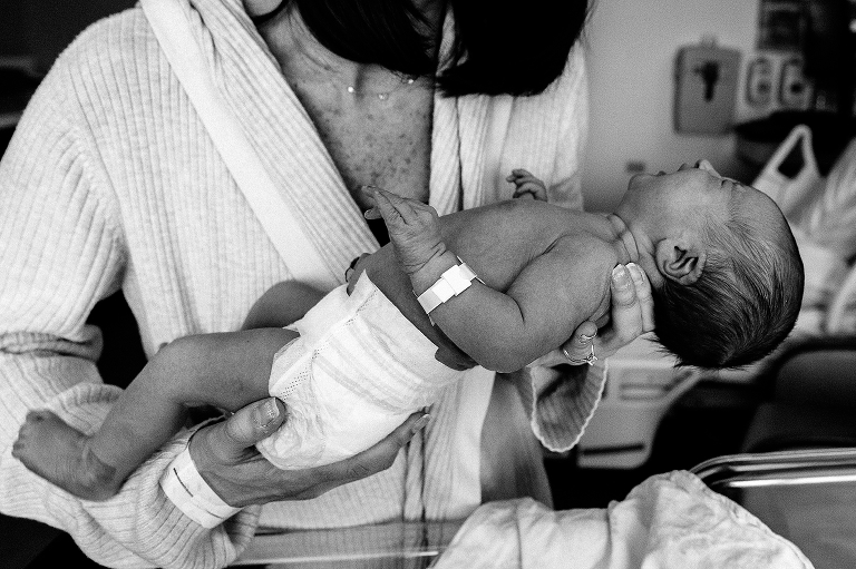 Black and white. Mother holds naked newborn baby in hospital.
