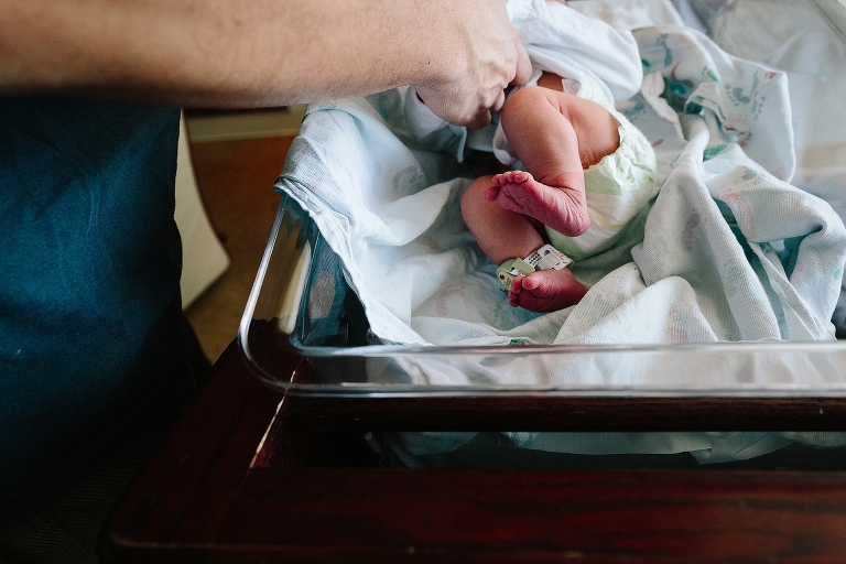 Father changes newborn baby's diaper in hospital.