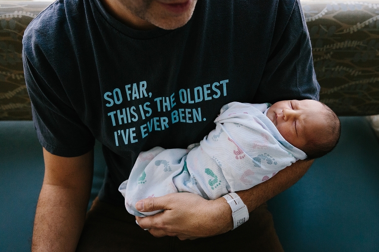 Father holds newborn baby in hospital room