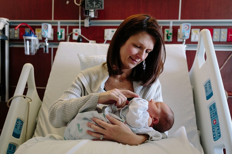 Mother cradles newborn baby in hospital.