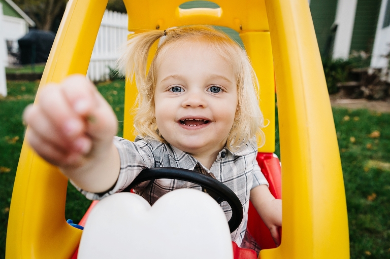 Little girl playing outside drives in toy car