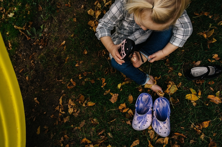 Little girl outside puts shoes on her bare feet