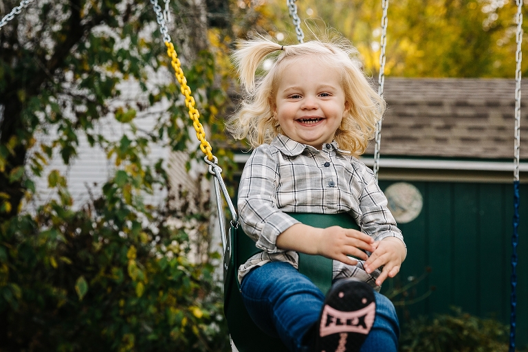 Young girl laughs while swinging in baby swing