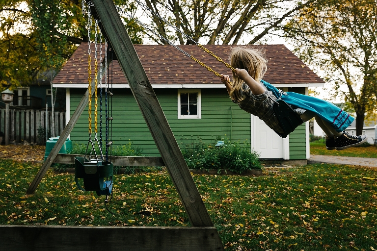 Young girl swings outside on swing set