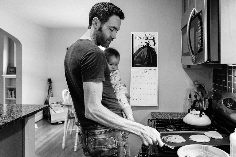 Dad holds 7month old while flipping pancakes 