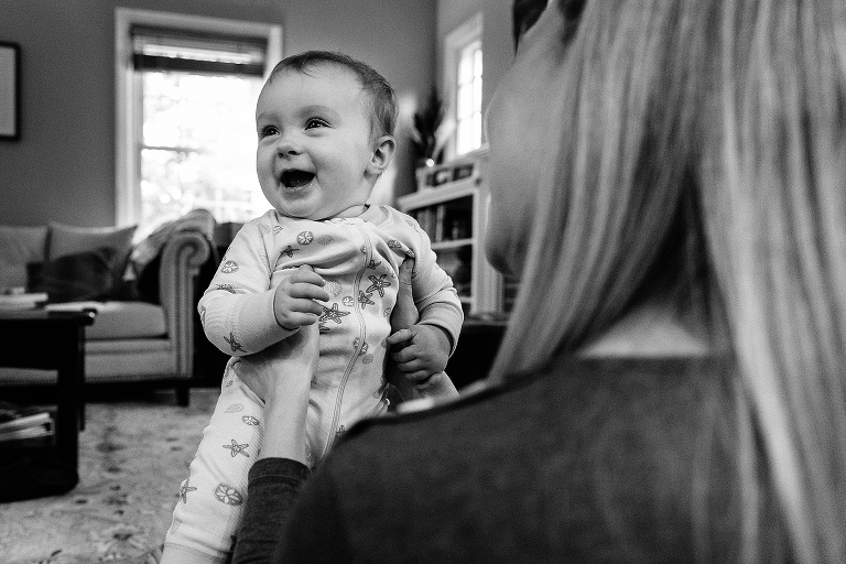 7month old girl smiles big on her mother's lap white dad makes Sunday morning pancakes