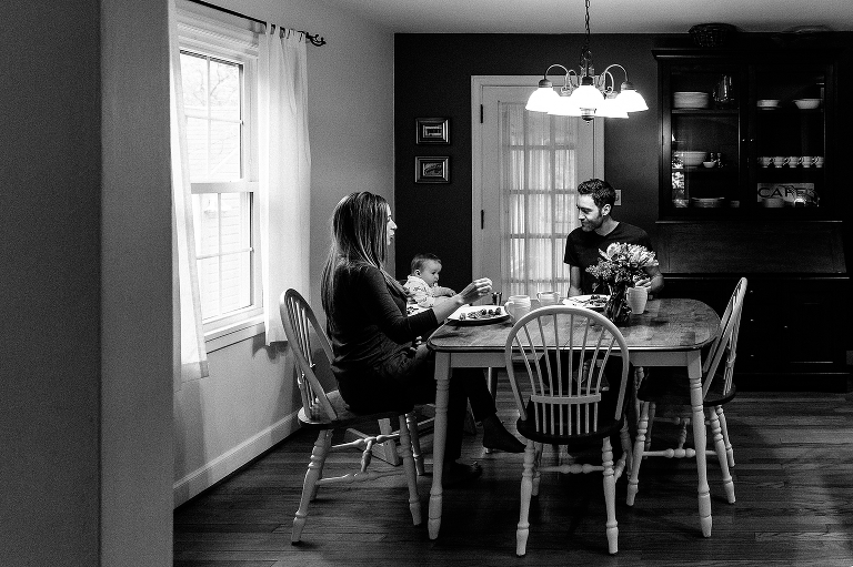 Black and white. Family sits at breakfast table together 
