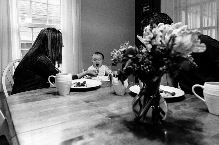 Mom feeds baby, baby yawns. Sunday morning pancakes