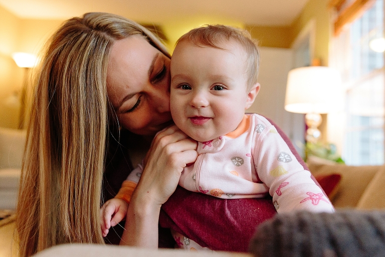 Mom kisses baby girl on the couch 