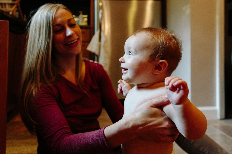 Daughter smiles as mom undresses her for a sink bath 