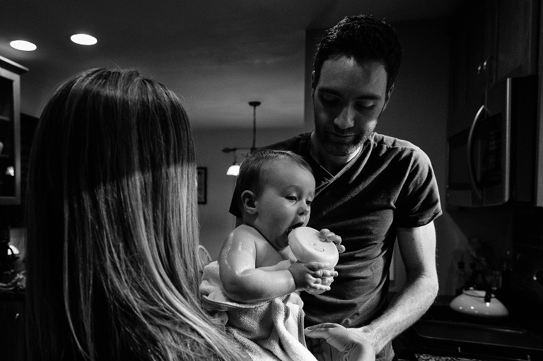 Black and white. Daugher in towel from sink bath chews on plastic duck 