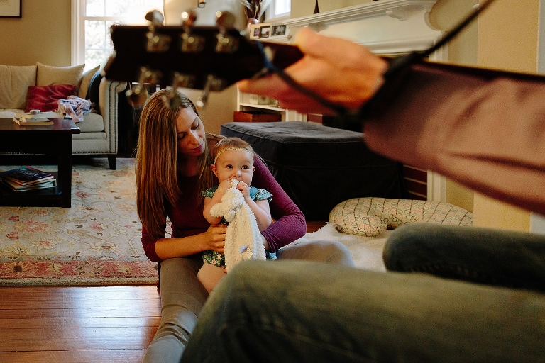 Dad plays guitar while baby girl and mom listen 