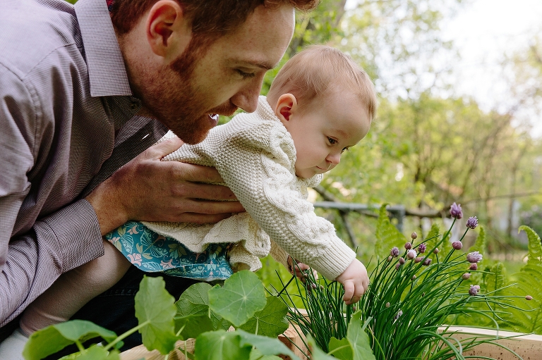 Baby girl touches green onion plants in the garden 