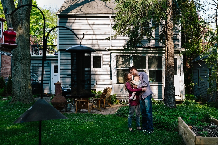 Family of three hugs in backyard. 