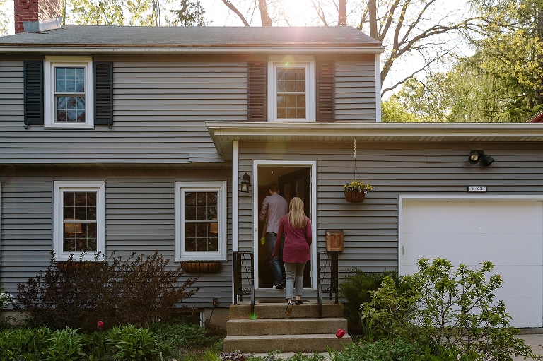 Family walks into the house with the sun shining down in spring during a Sunday morning pancakes photo session