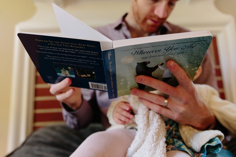 Dad reads book to daughter on his lap
