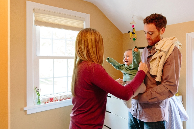 7 month old cries as her dad holds her and her mother changes her for a nap in a Sunday morning pancakes photo session