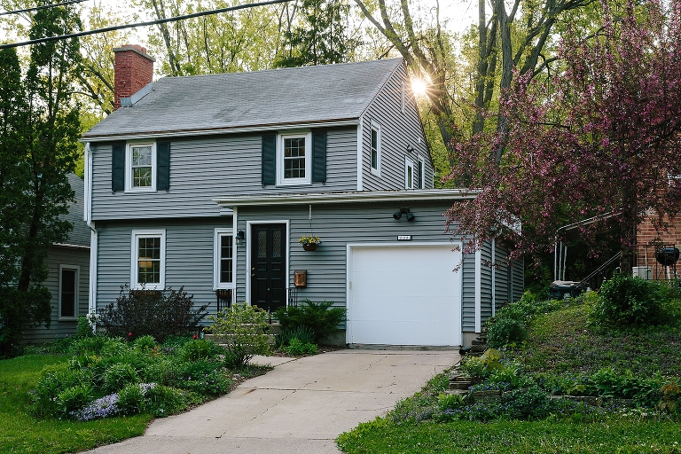 Sunrise peeks behind a gray house. 