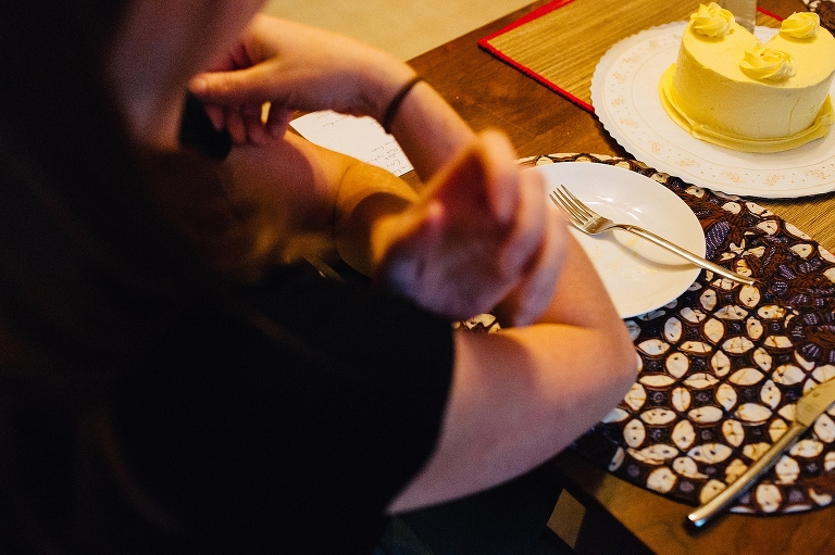 Woman sitting at table with empty plate and yellow cake missing pieces