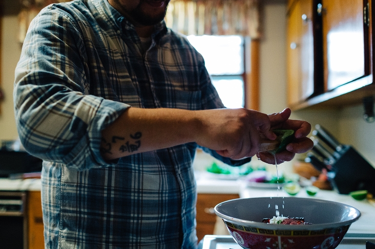 Man in kitchen squeezing lime into bowl of steak