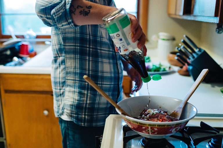Man in kitchen pouring sauce into bowl of steak